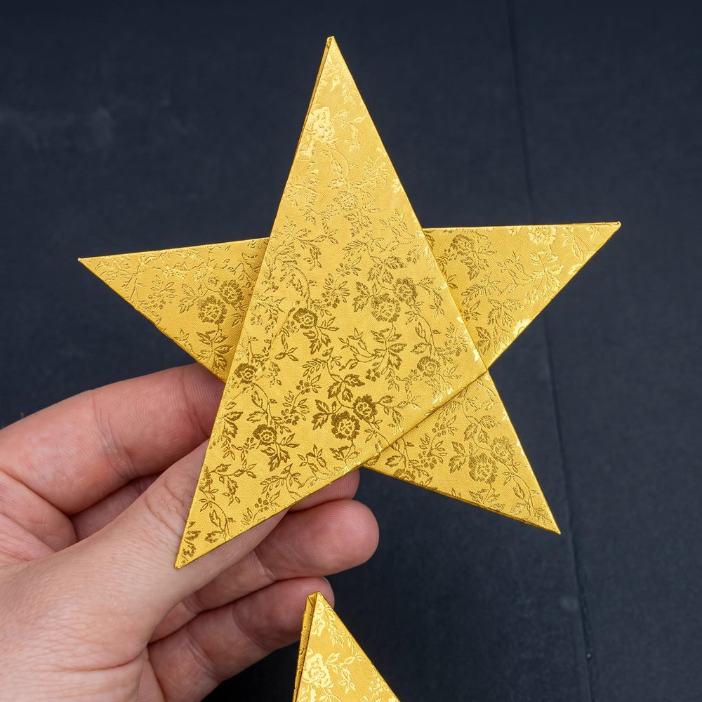 A folded gold origami star held in a hand